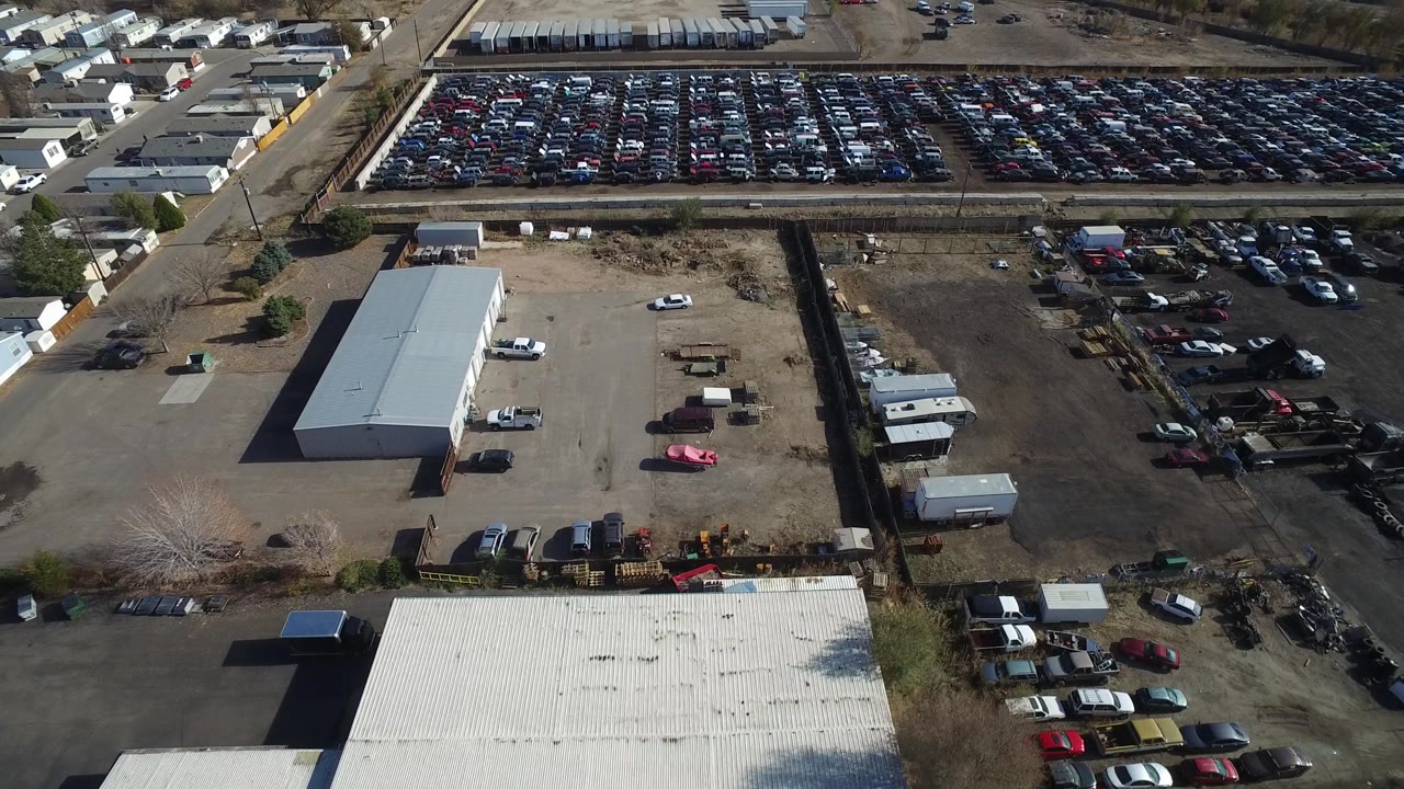 Aerial view across a factory area and large car storage lot.