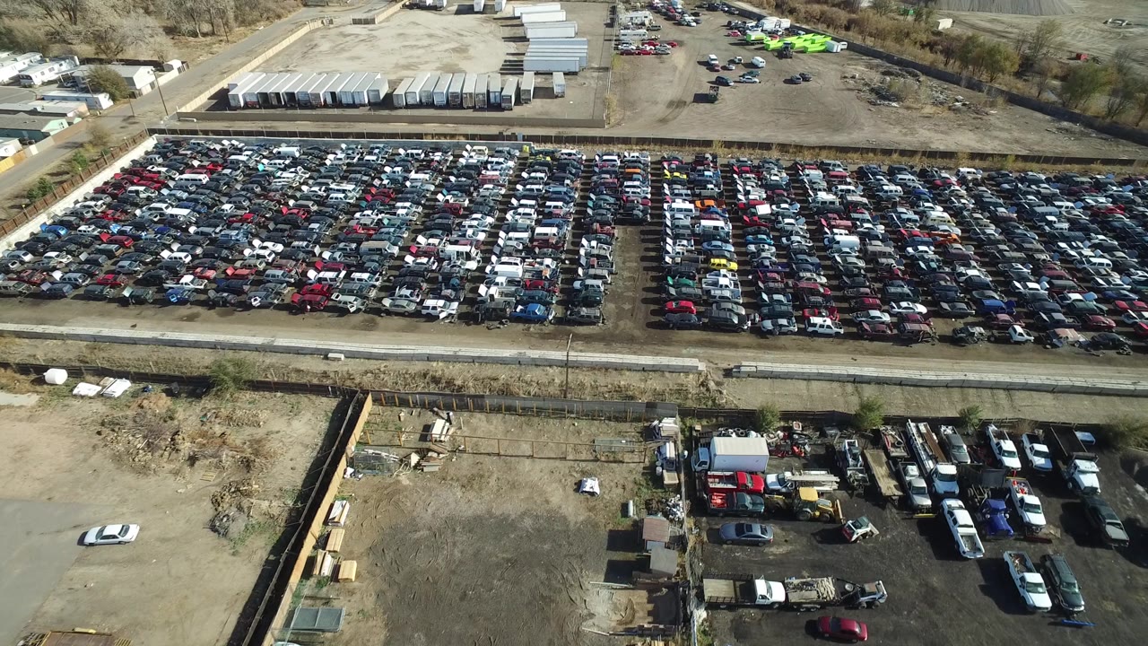 Aerial view across a dense car lot with a smaller work yard in front.