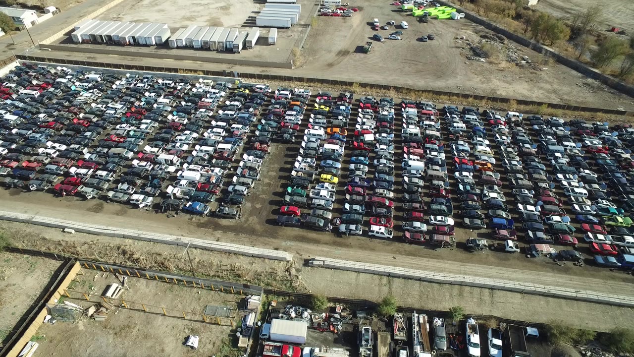 Wide aerial of a crowded parking lot with service road and utility yard nearby.