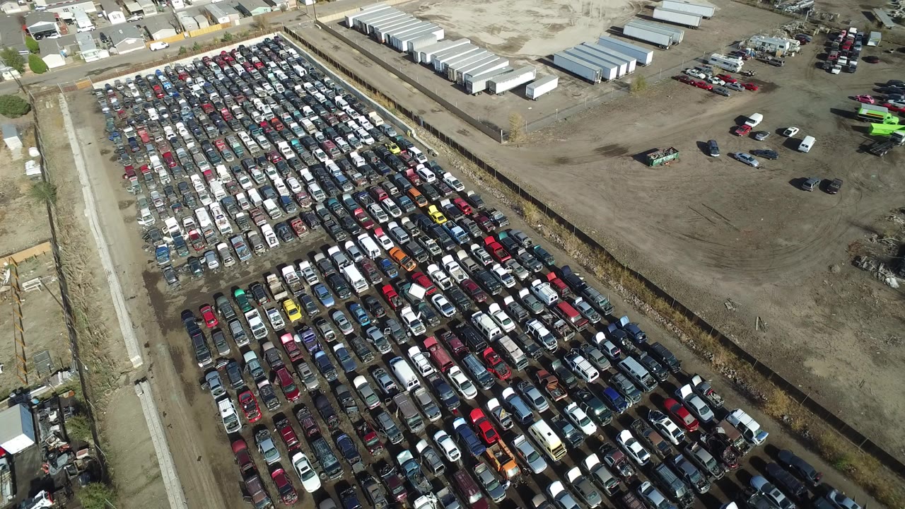 Aerial view of rows of parked cars beside an industrial yard.