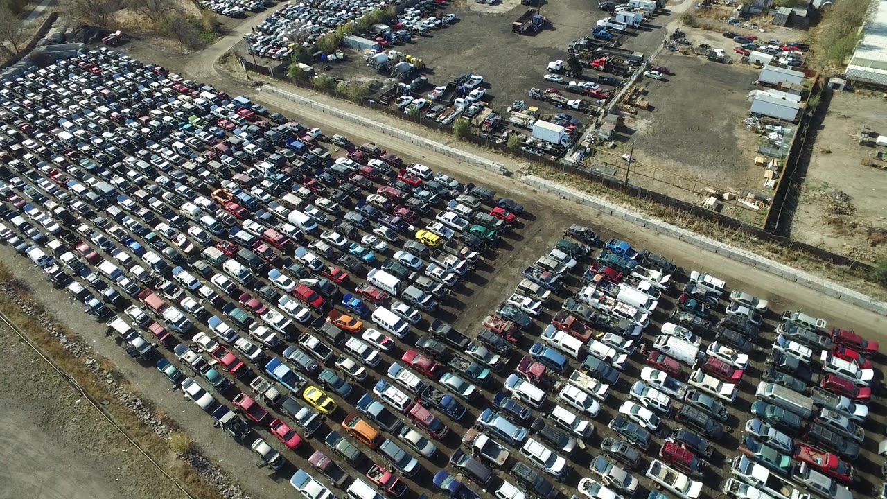 Overhead view of rows of parked cars beside a dirt road.