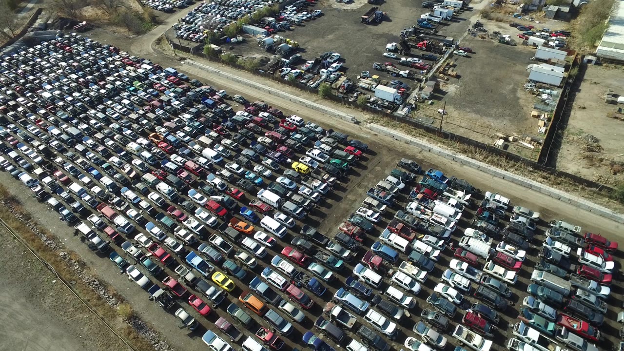 Aerial frame in Westminster, Colorado with tightly arranged car rows, fenced yard edges, small service structures, and no visible people.