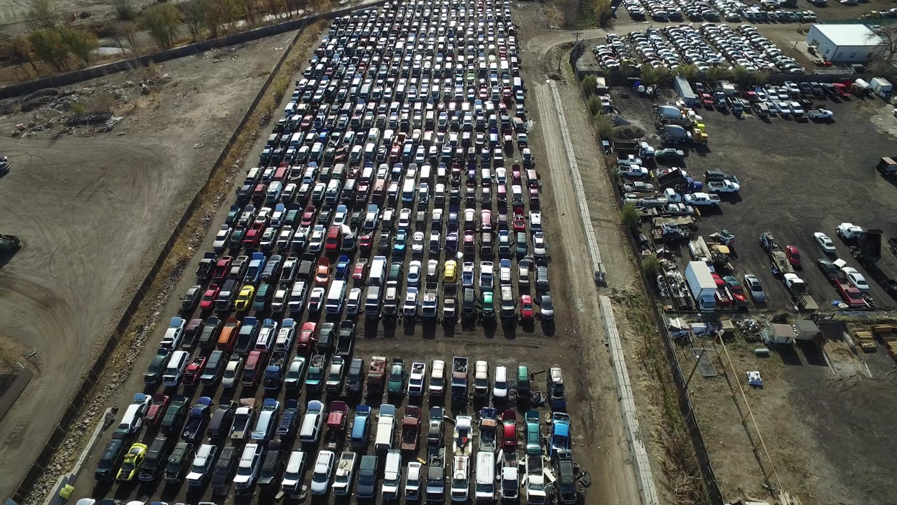 Opening aerial frame over a large parked vehicle lot in Westminster, Colorado, with railroad tracks or a service corridor along the side and no visible people.