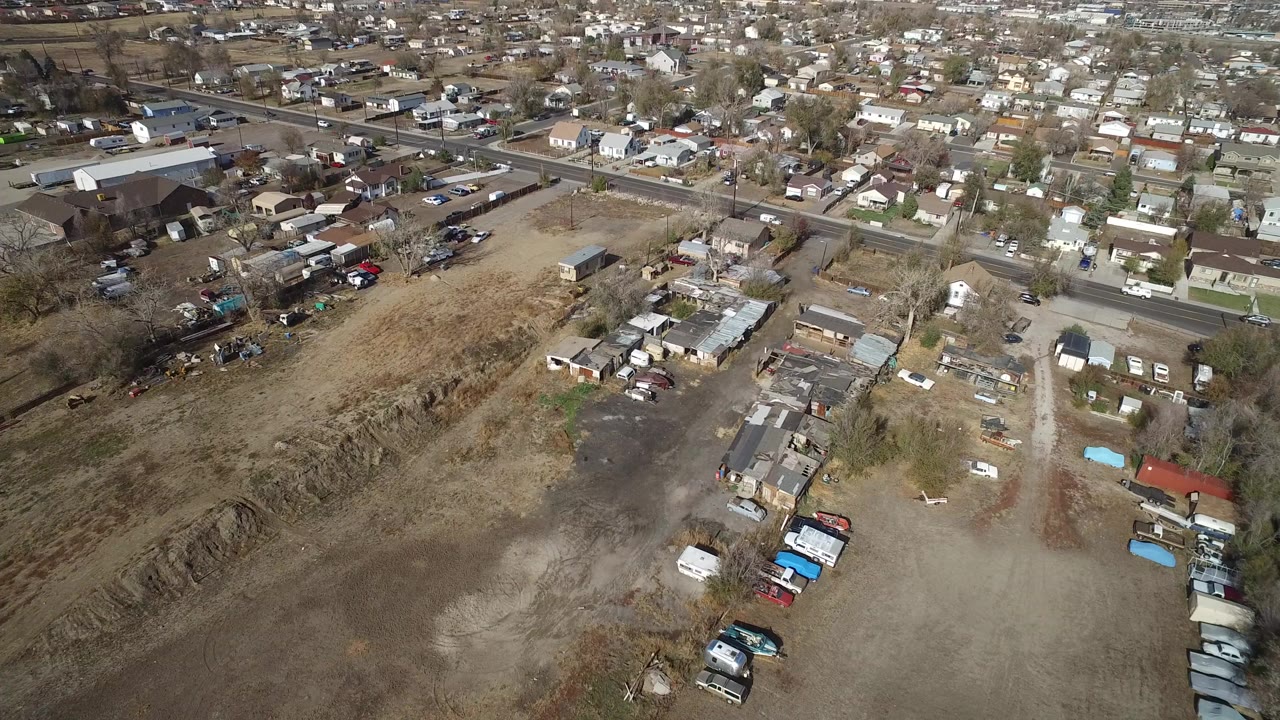 Aerial view of dry lots, houses, roads, and parked vehicles.