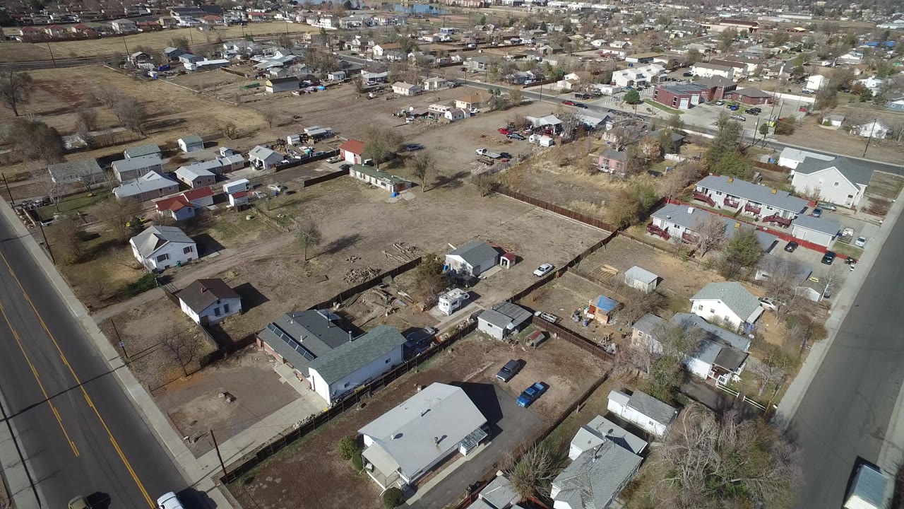 Aerial view of houses, roads, fenced lots, and dry grass.