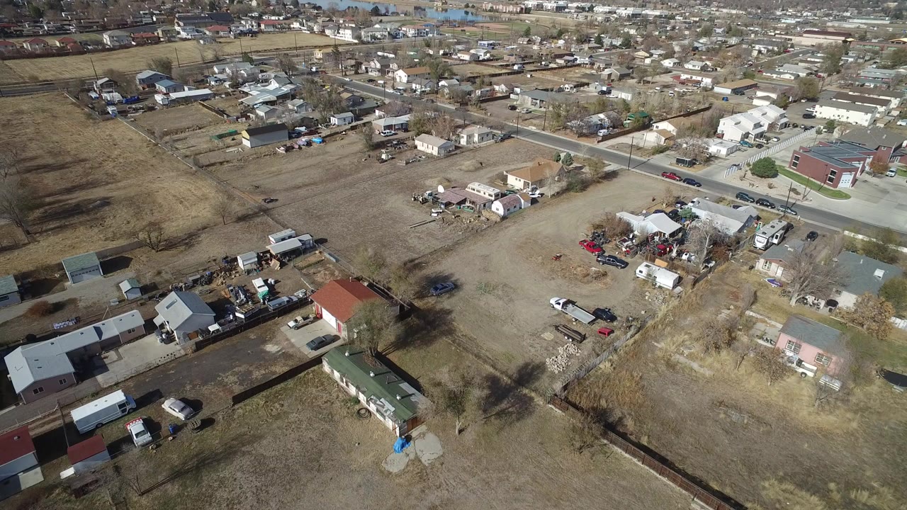Aerial view over dry suburban lots, homes, sheds, and a paved road.