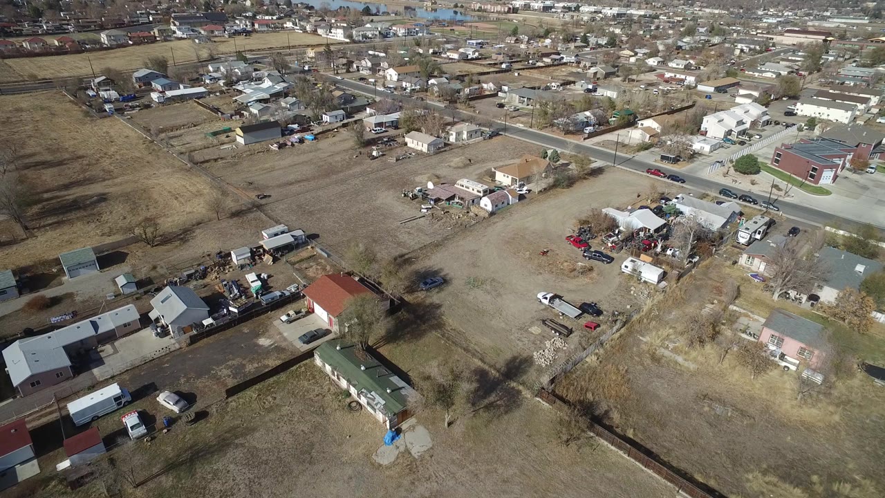 Second aerial frame in Westminster, Colorado showing fenced or divided lots, small buildings, trailers, parked cars, and no visible people.