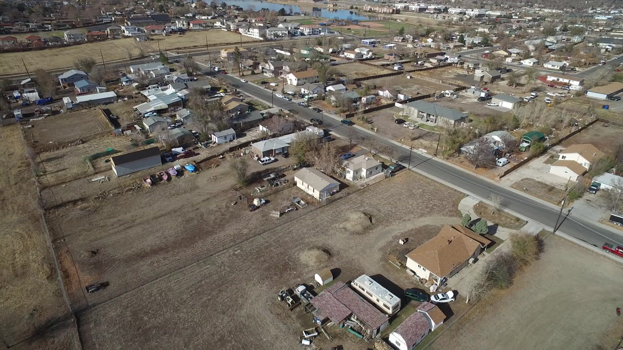 Aerial view of residential blocks, open lots, roads, and houses.