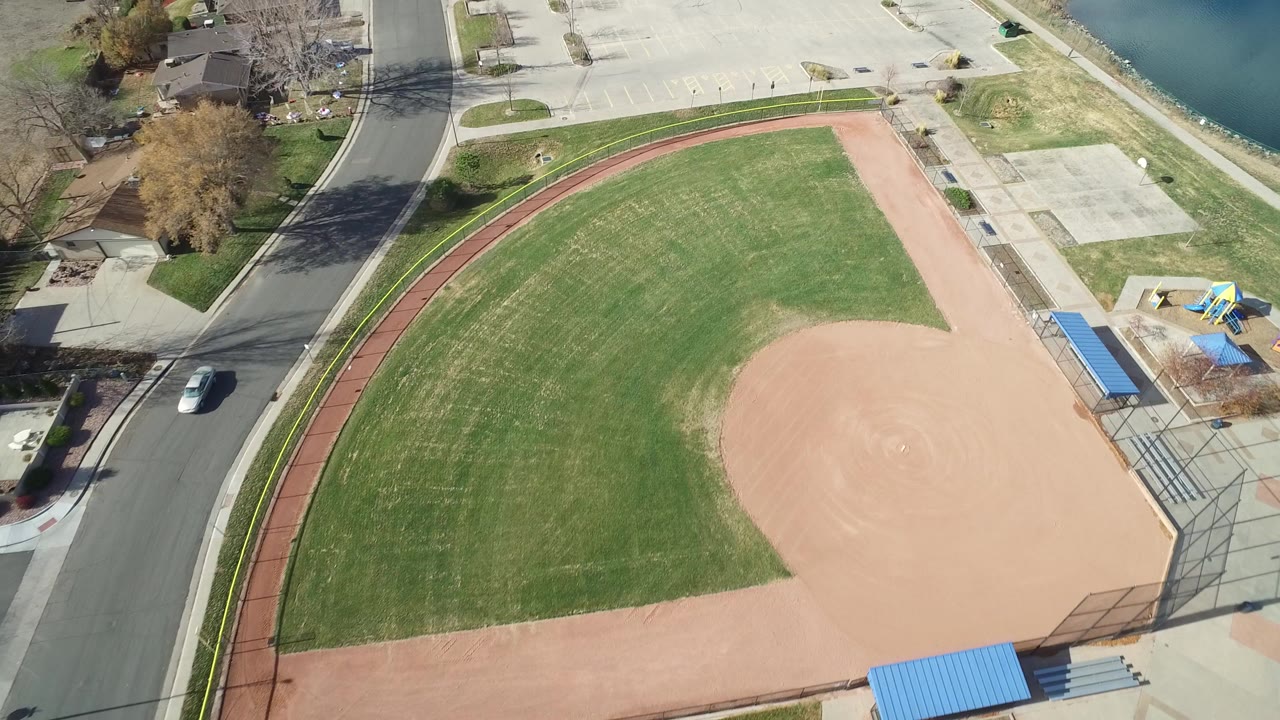 Aerial view of a baseball field beside a road and parking lot.