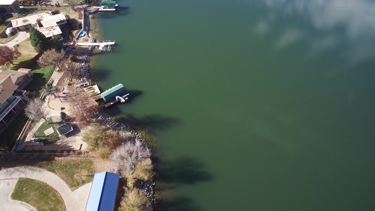 Aerial view of aqua green lake beside homes and docks.