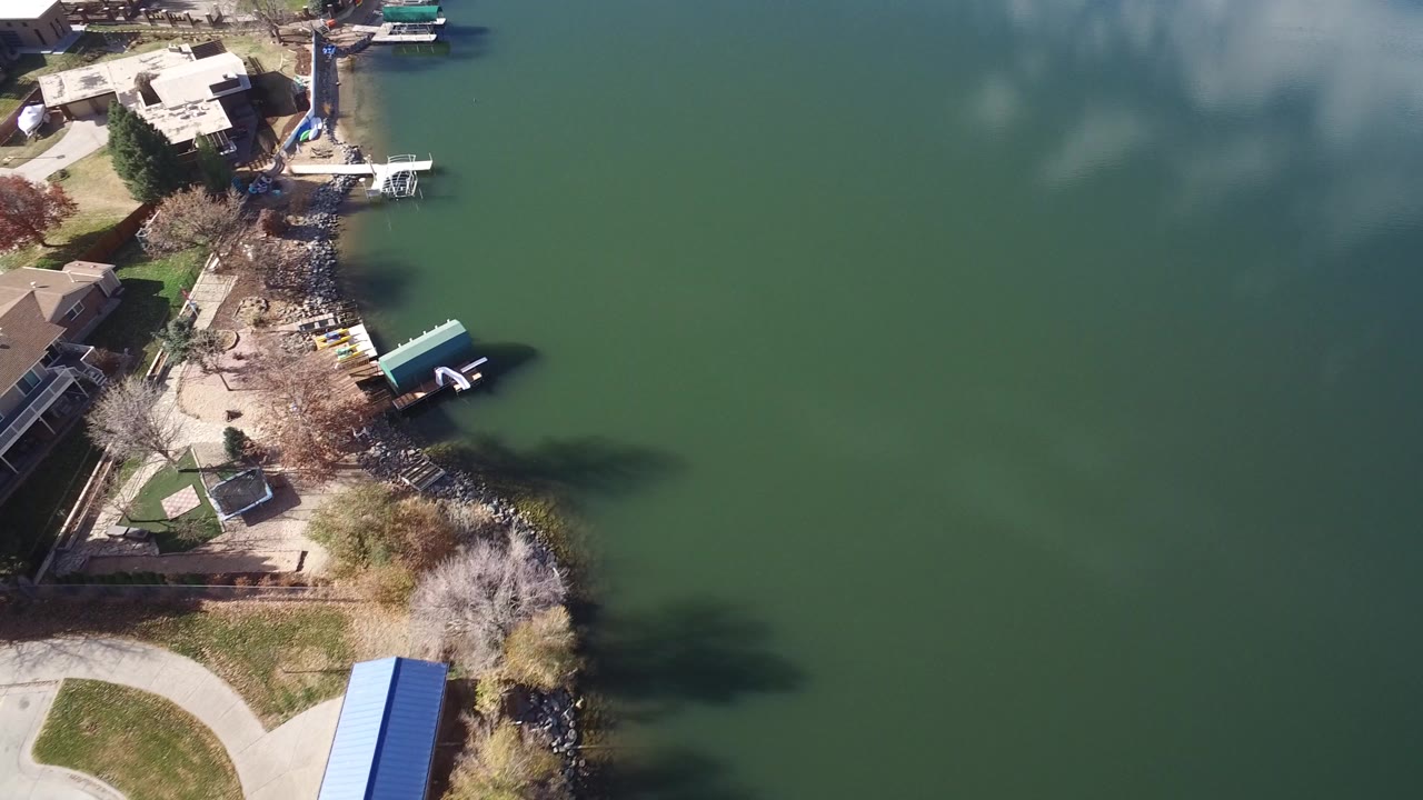 Aerial view in Westminster, Colorado showing the shoreline shifted closer to center, with docks, boats, leafless trees, and no visible people.