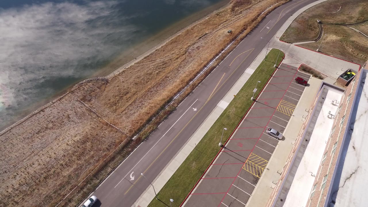 Overhead road, parking lot, building roof, water, and dry grass