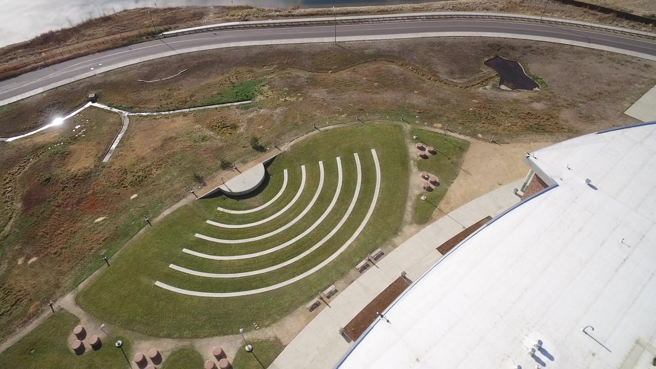 Aerial view of a white roof beside a curved green lawn and road.