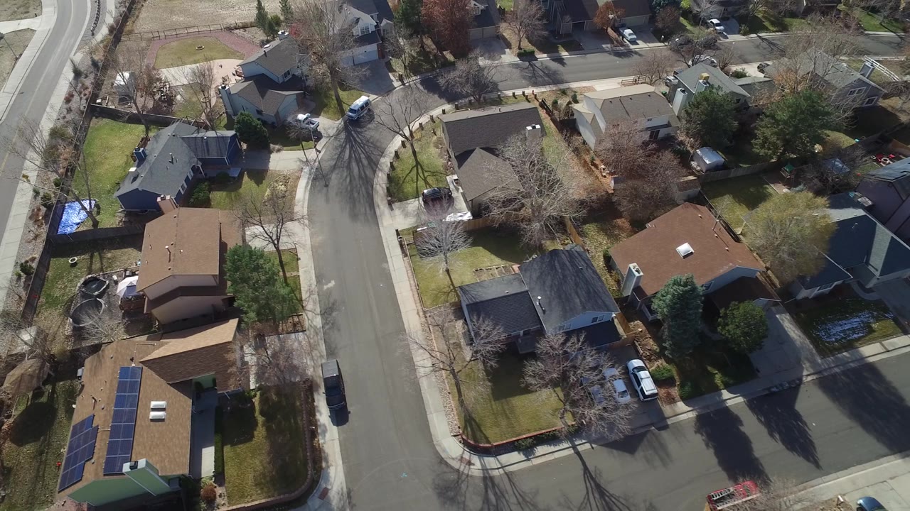 Overhead Westminster, Colorado neighborhood view showing detached houses, leafless trees, green lawns, and a curved road, with no visible people.