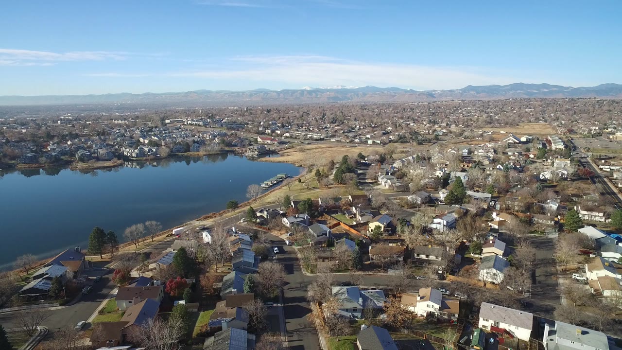Aerial view of suburban houses beside a lake with mountains in the distance.