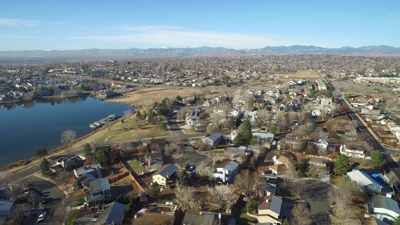 Aerial view of suburban homes beside a lake under a clear blue sky.