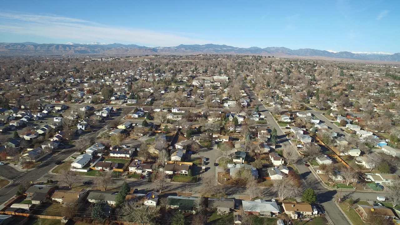 Aerial view over suburban homes and streets with mountains in the distance
