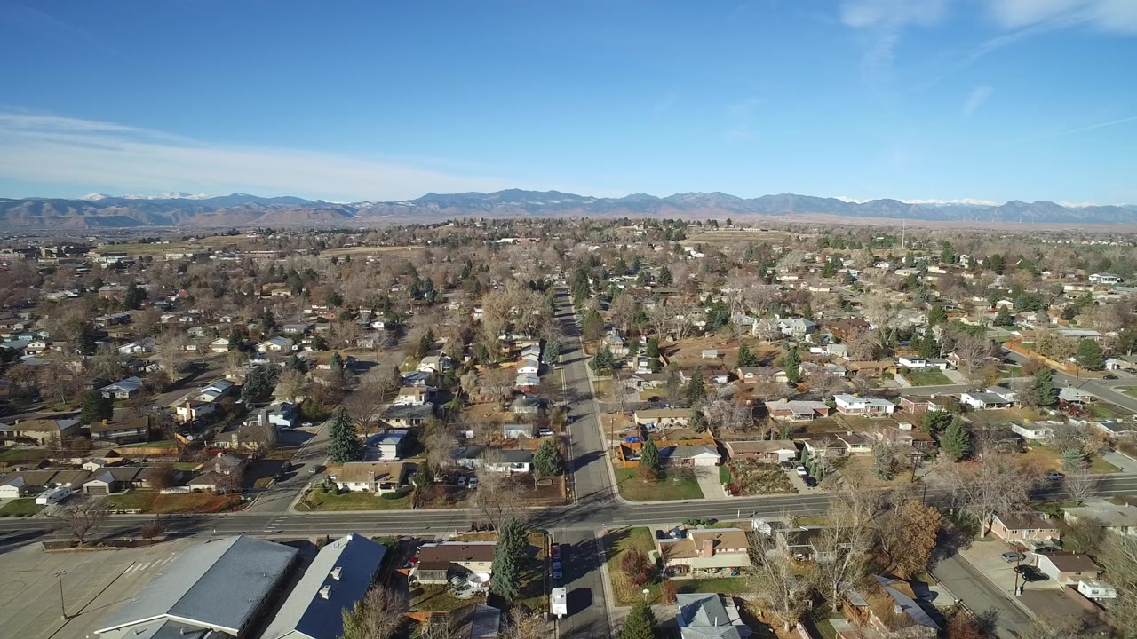 Suburban aerial looking across houses toward a mountain range.