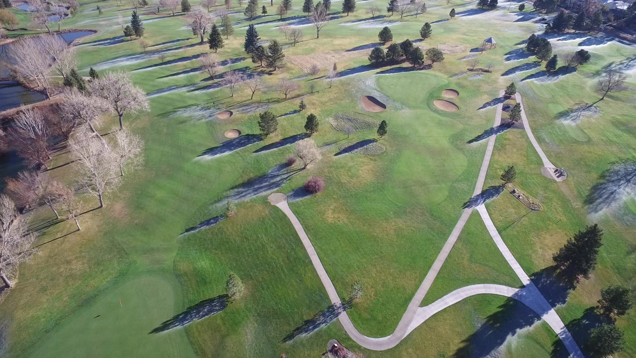 Aerial view of golf course greens, cart paths, trees, and sand bunkers.