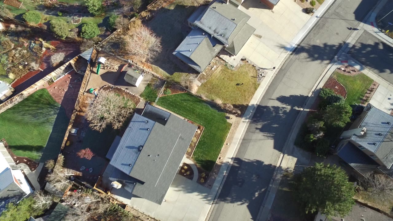 Top-down neighborhood view with a large lawn, fenced yards, and residential roofs.