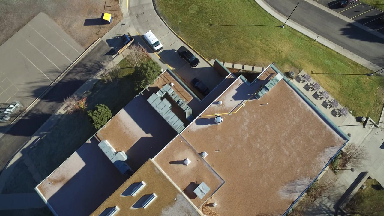 Overhead view of a tan-roofed building beside roads and lawn