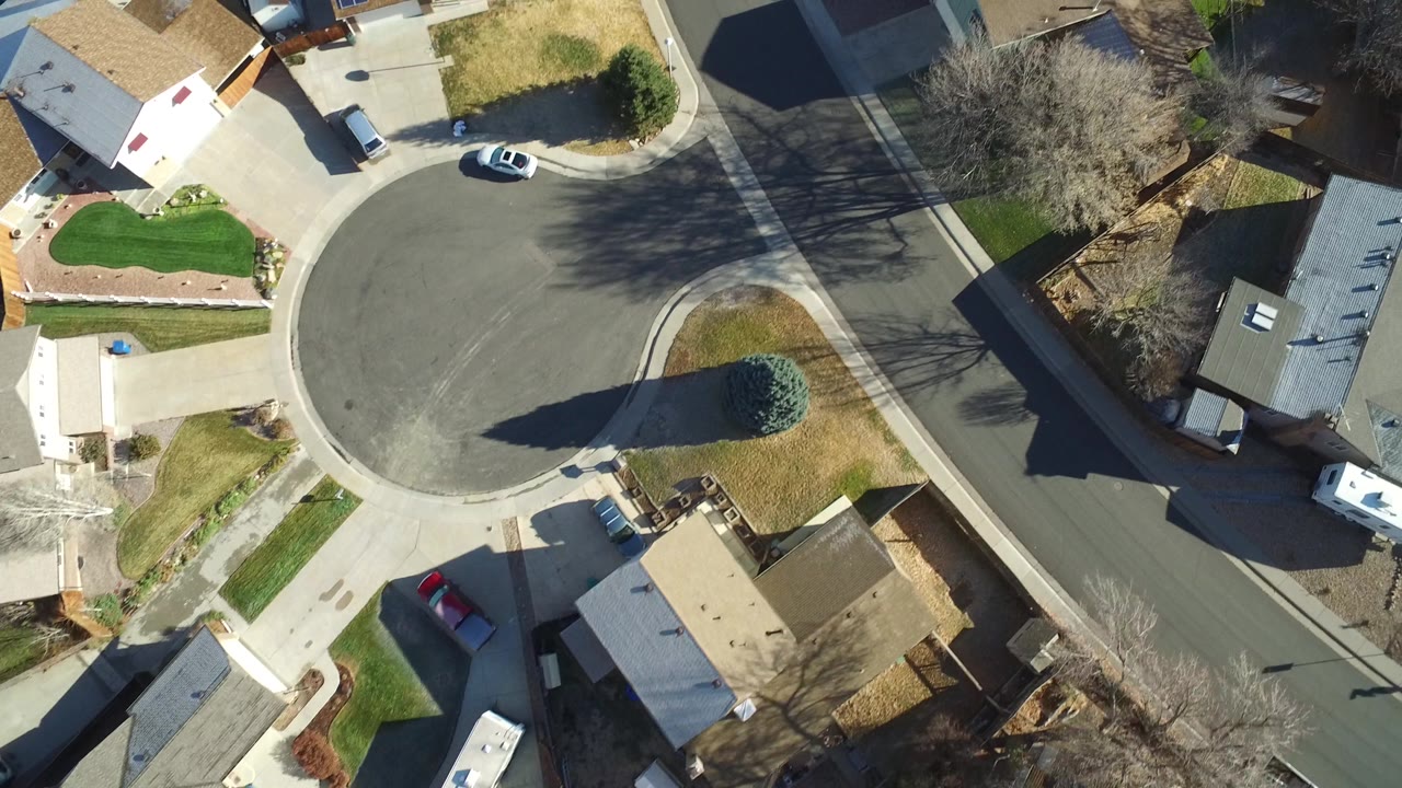 Aerial view in Westminster, Colorado showing the circular end of a residential street, several homes, parked vehicles, bare trees, and no visible people.