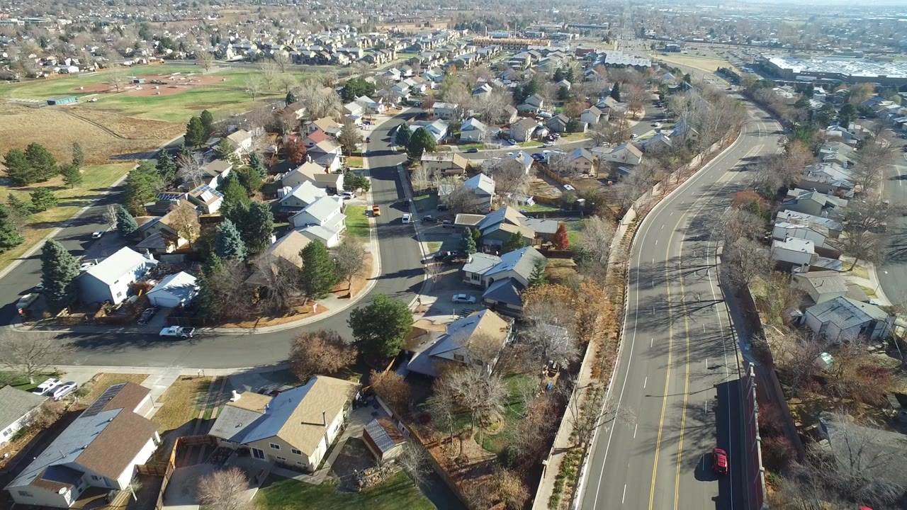 Aerial view of suburban houses, streets, trees, and a divided road.