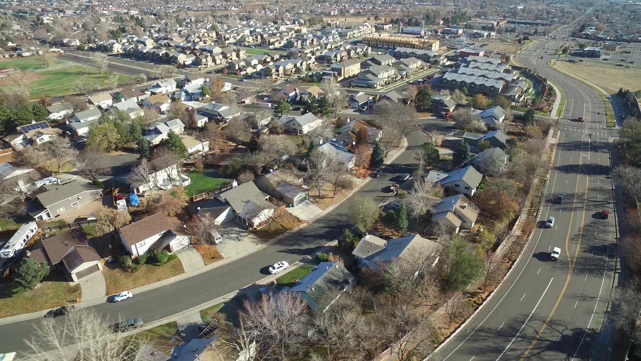 Drone view over houses, trees, and moving road traffic