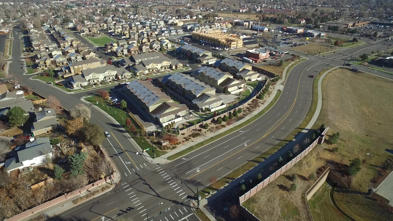 Aerial view of a suburban intersection beside rows of homes and grass lots.