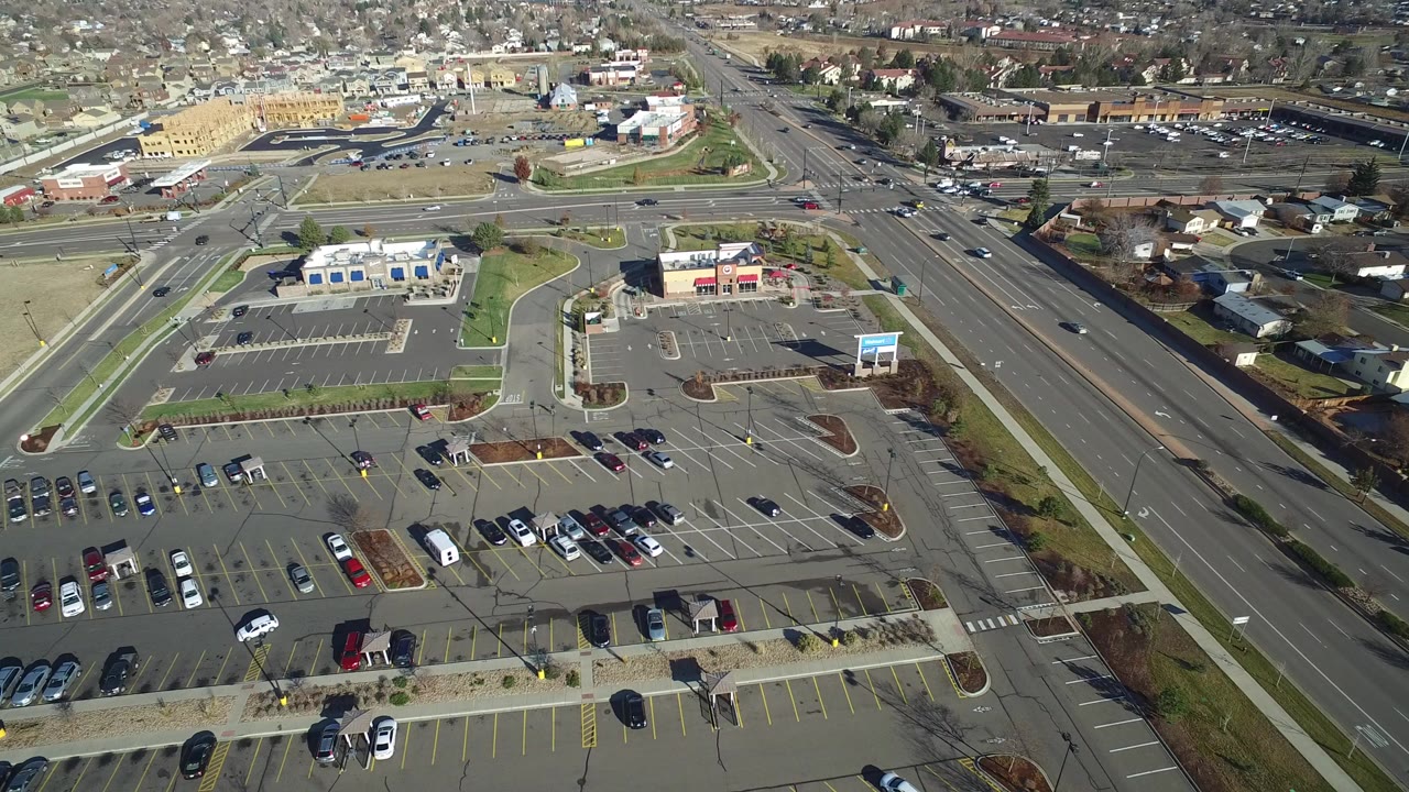 Aerial view of a parking lot beside a multi-lane road and suburban homes.