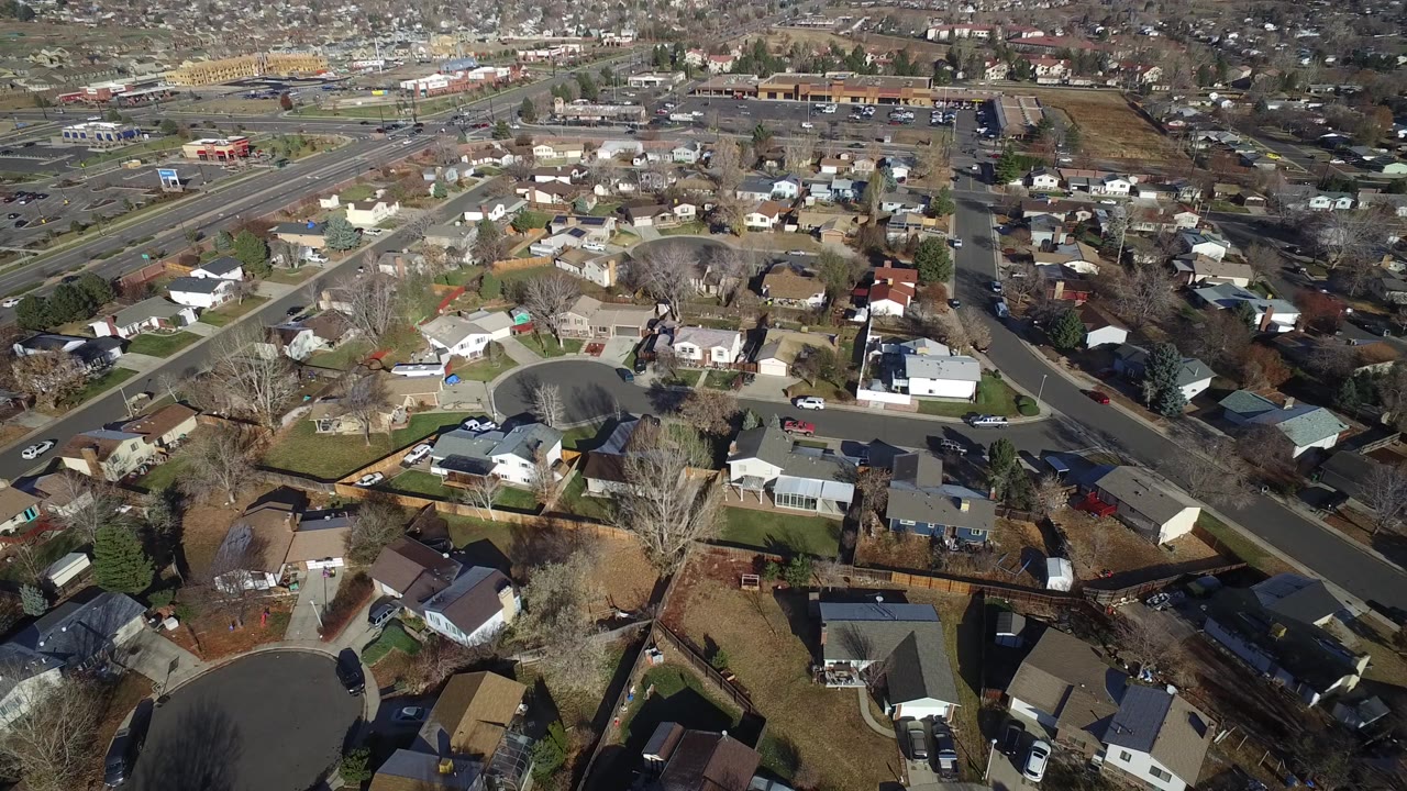 Aerial view over suburban houses, cul-de-sac streets, and backyards.