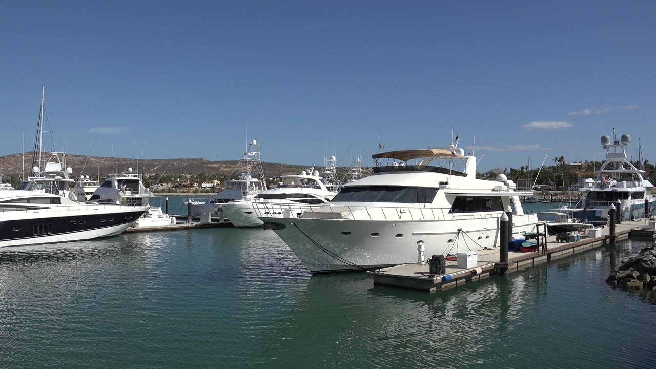 Marina yachts with dock reflections on green-blue water.