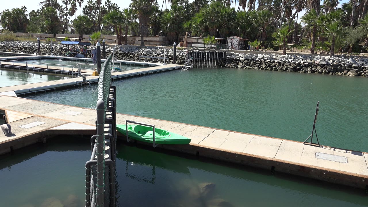 Green kayak along a dock with open water and rocks behind it.