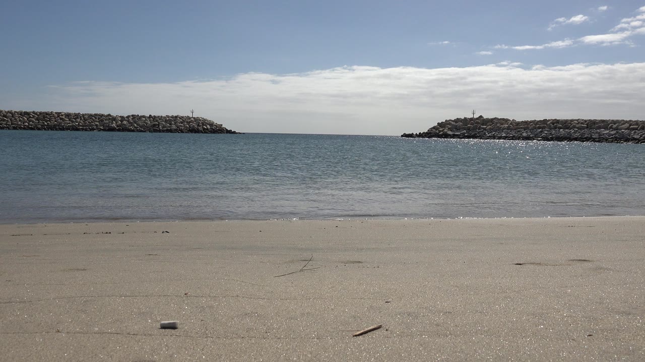 At one second, the San Jose del Cabo shoreline shows a thin wave line reaching the sand, with the right breakwater prominent and no visible people.