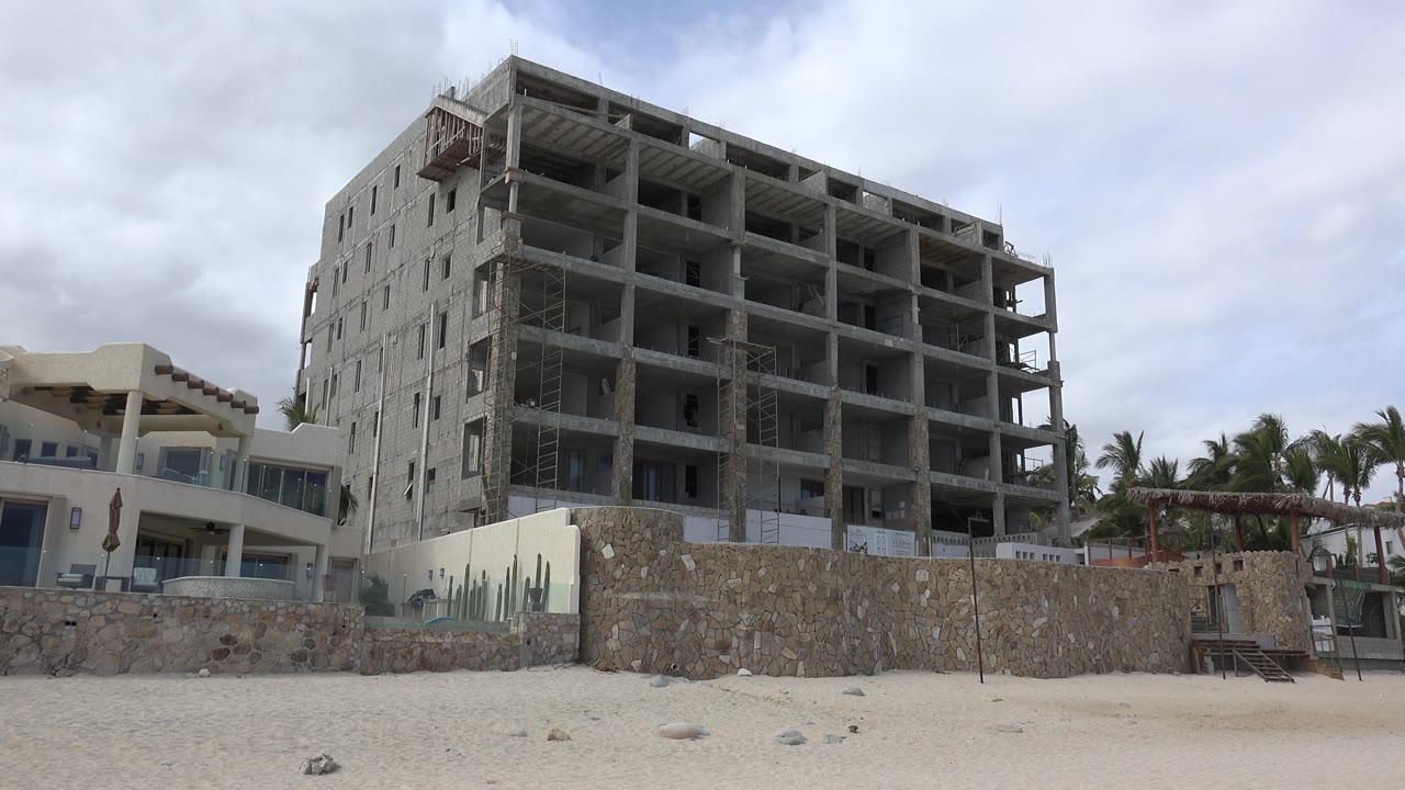 Abandoned multi-story building above beachside wall