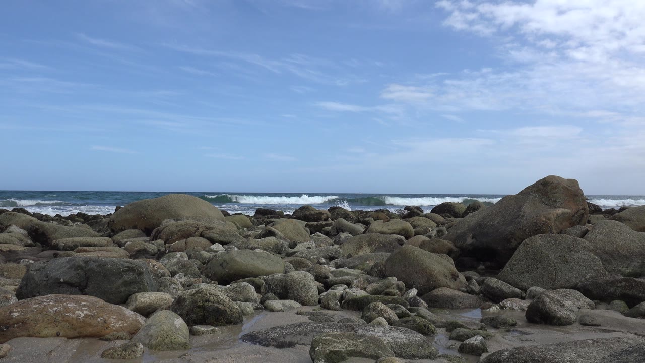 Rocky beach with ocean surf and blue sky