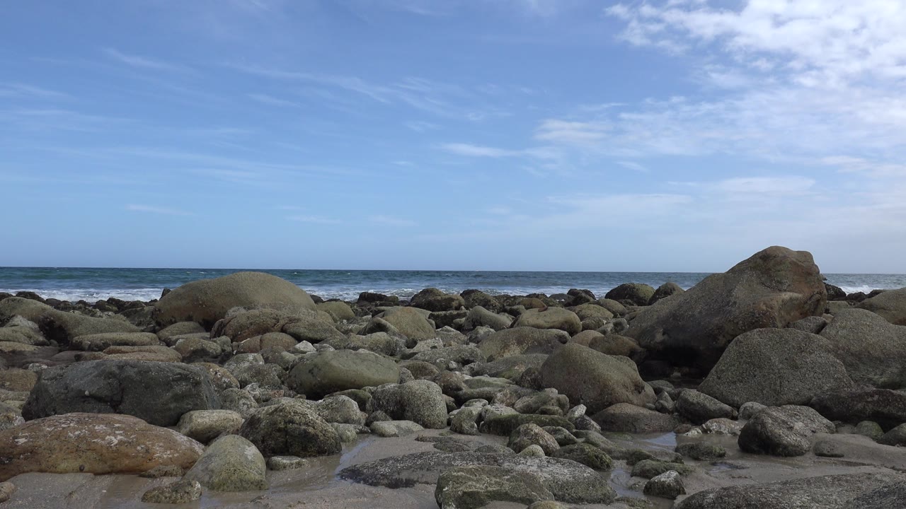 Stone-filled beach foreground with surf in the distance.