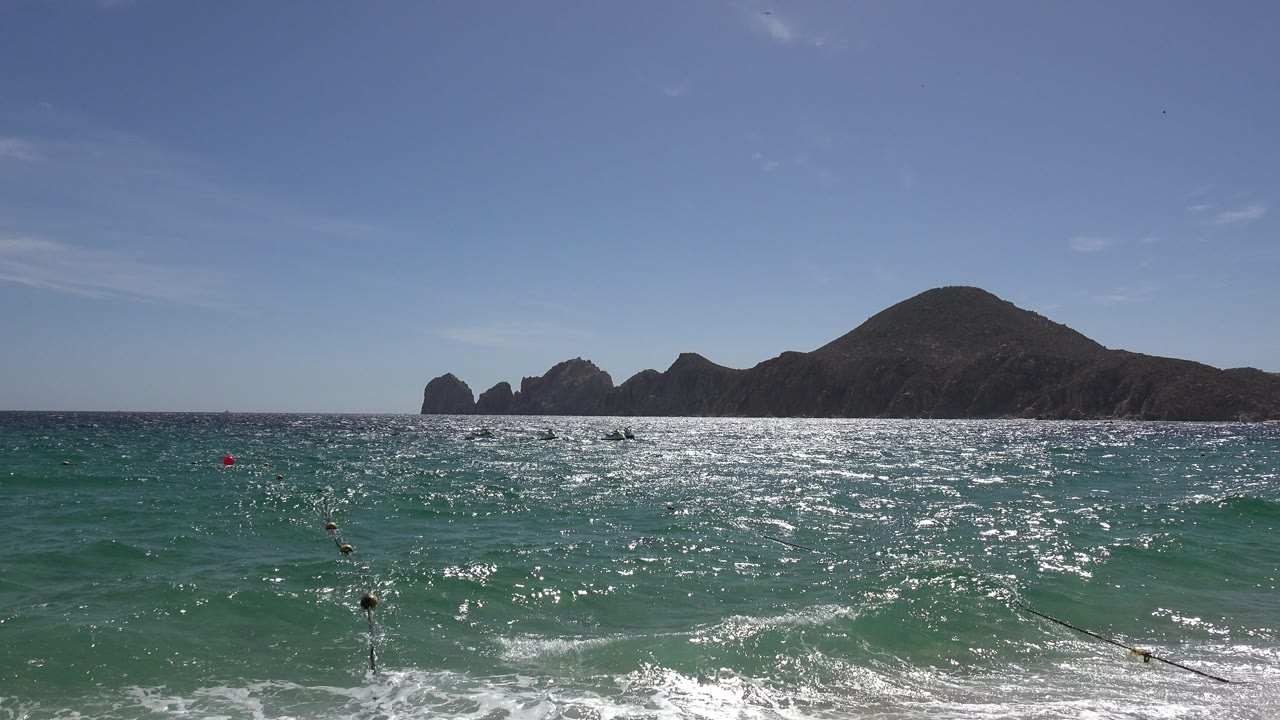 Ocean waves with distant mountains under a clear sky.