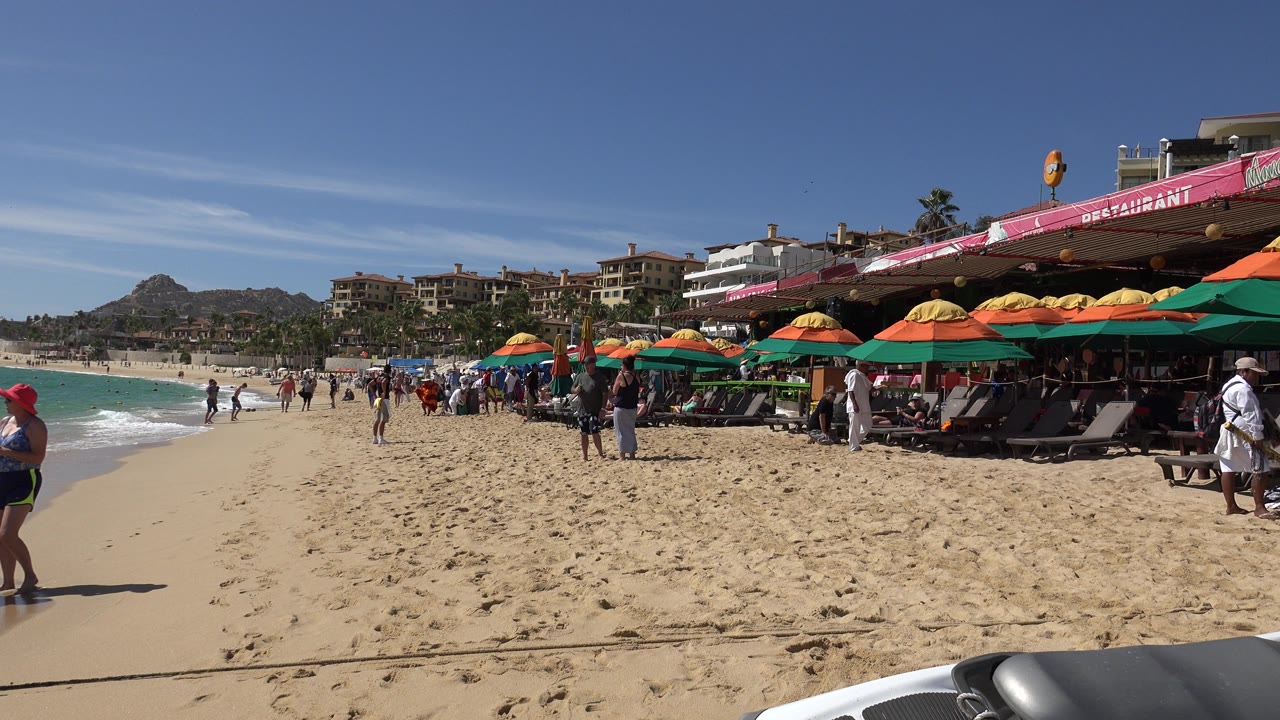 Beach shoreline with colorful umbrellas and people walking on sand