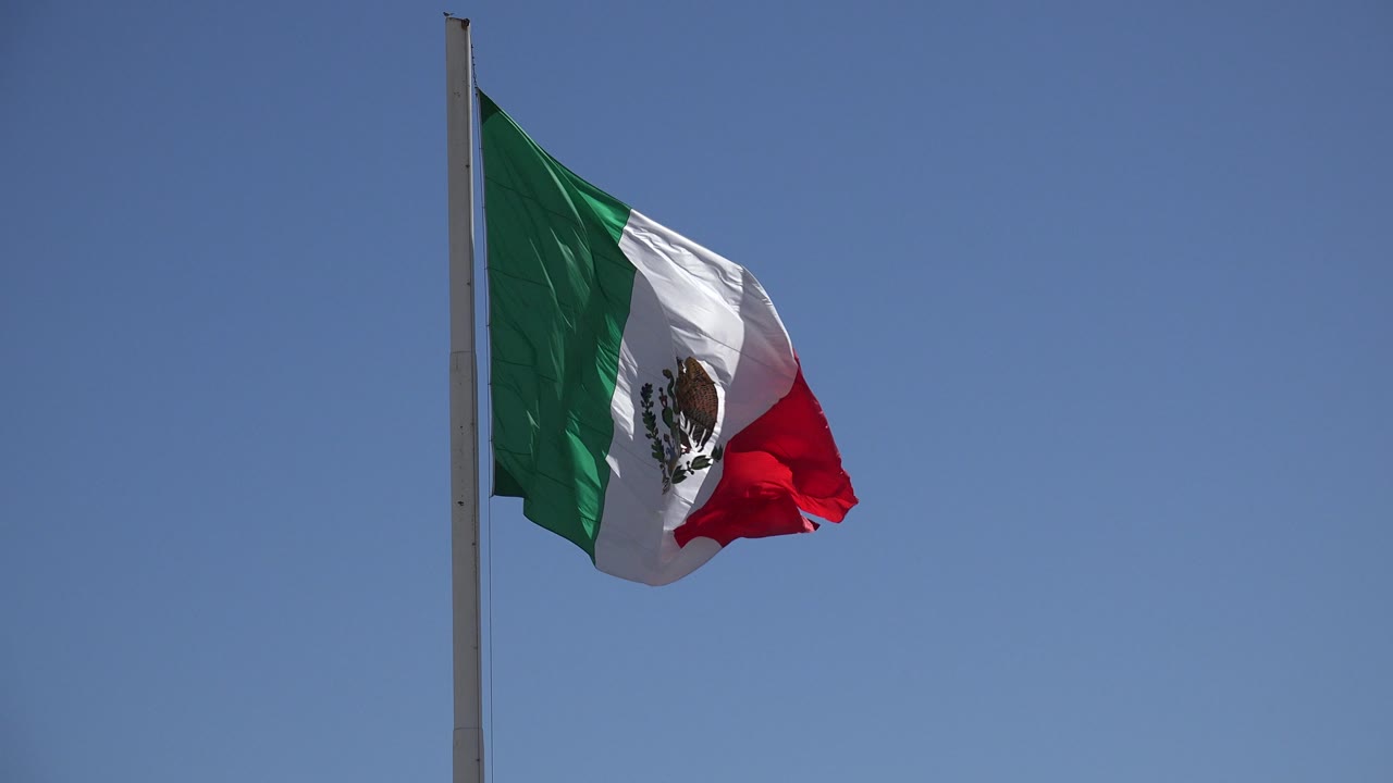 Mexican flag stretched outward in wind on a pole