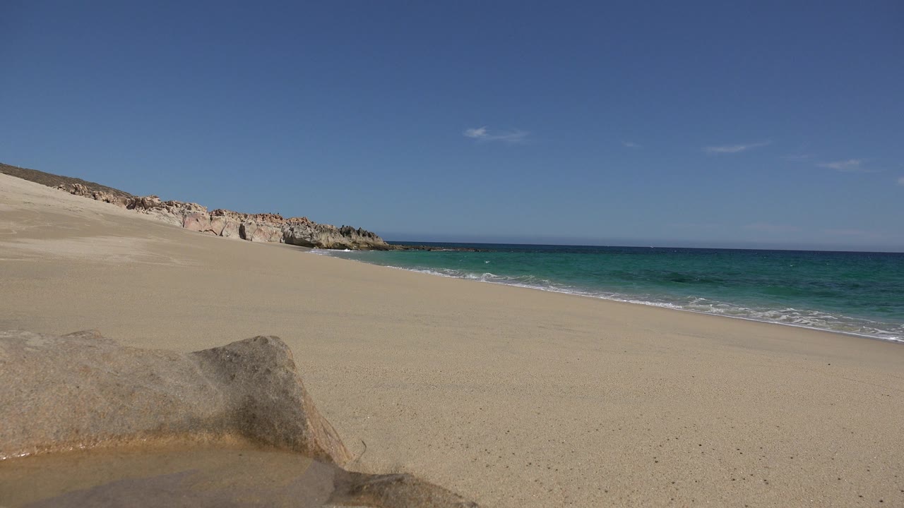 Open beach with rock wall and calm blue water