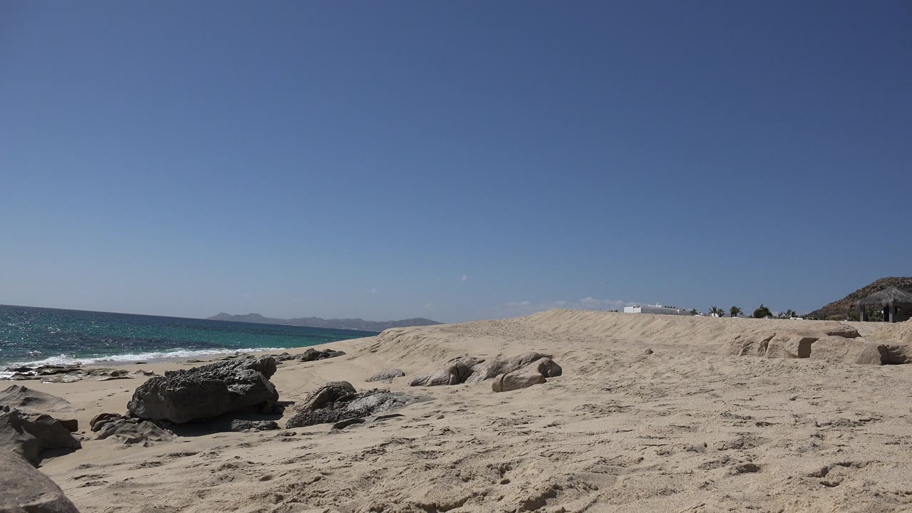 Rocky sand beach with blue ocean and clear sky
