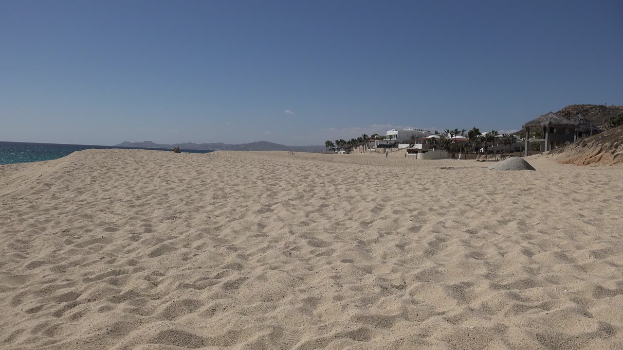 Wide sandy beach with ocean at left and beachfront buildings at right