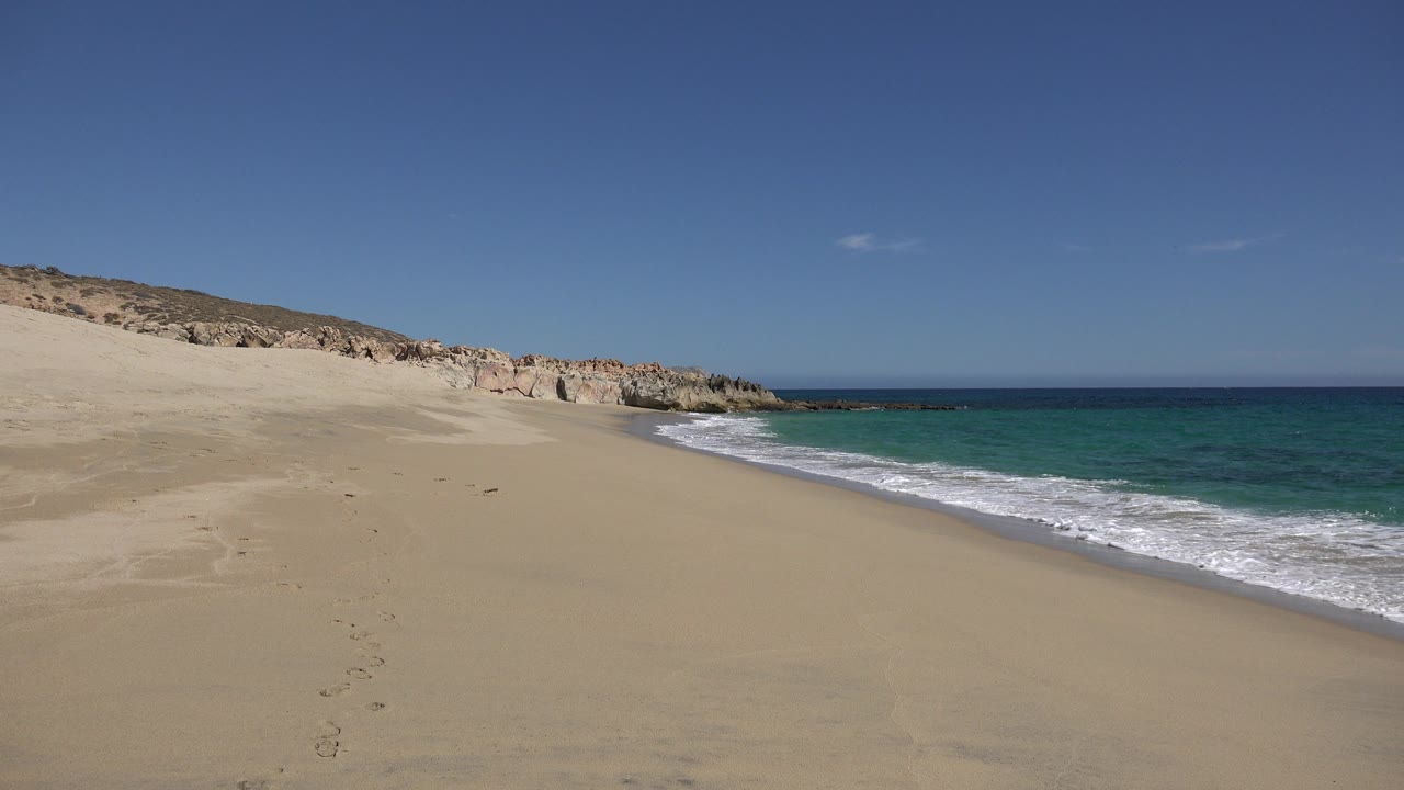 Bright empty beach with turquoise water and foam near the shore