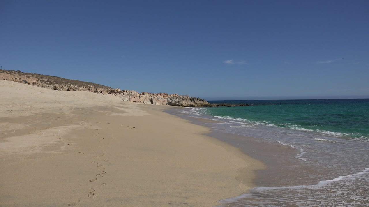 Turquoise water and foam beside an empty sand beach