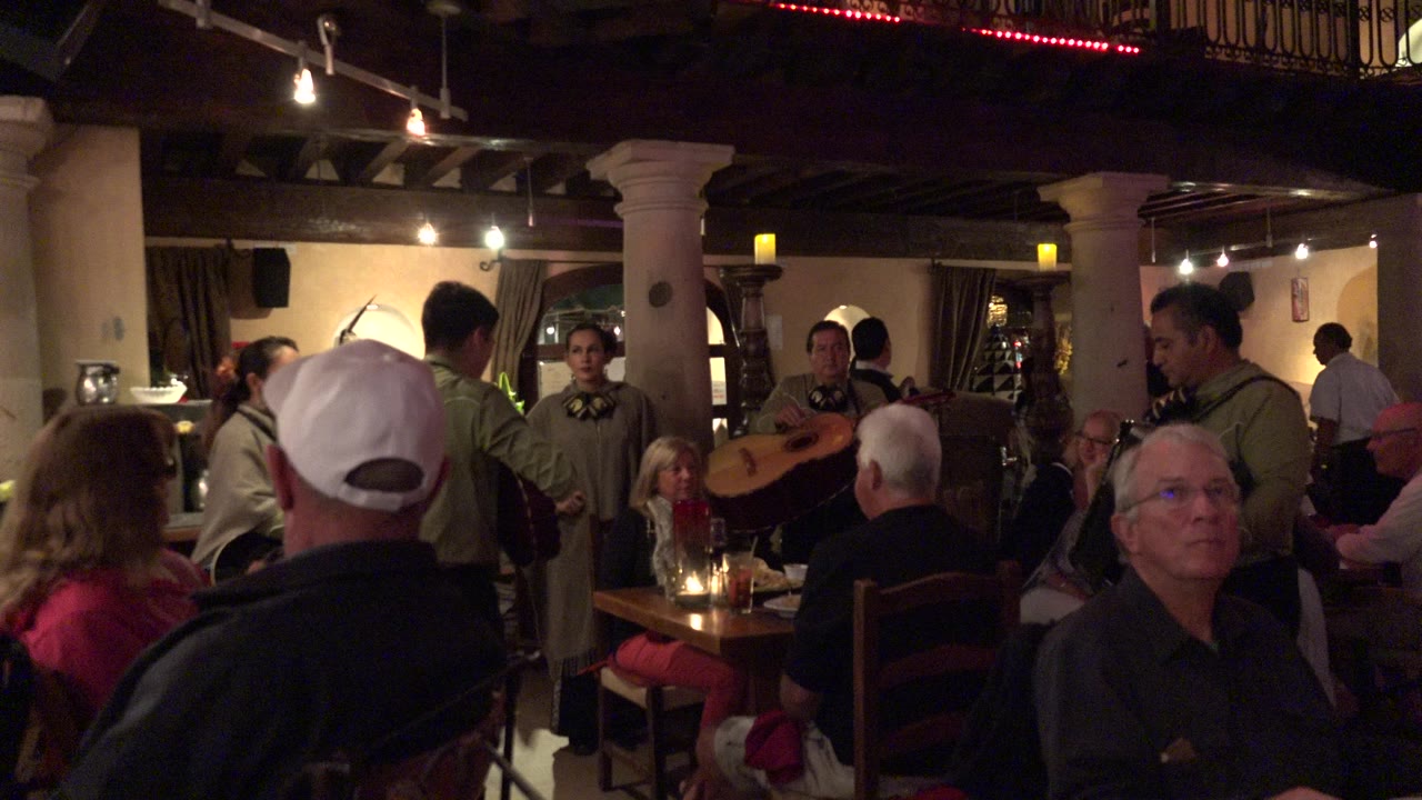 Seated diners watch musicians perform inside a warm restaurant room.