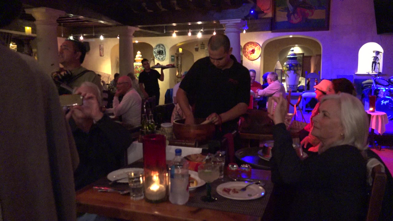 Restaurant table with older diners, a server, and colored stage lighting.
