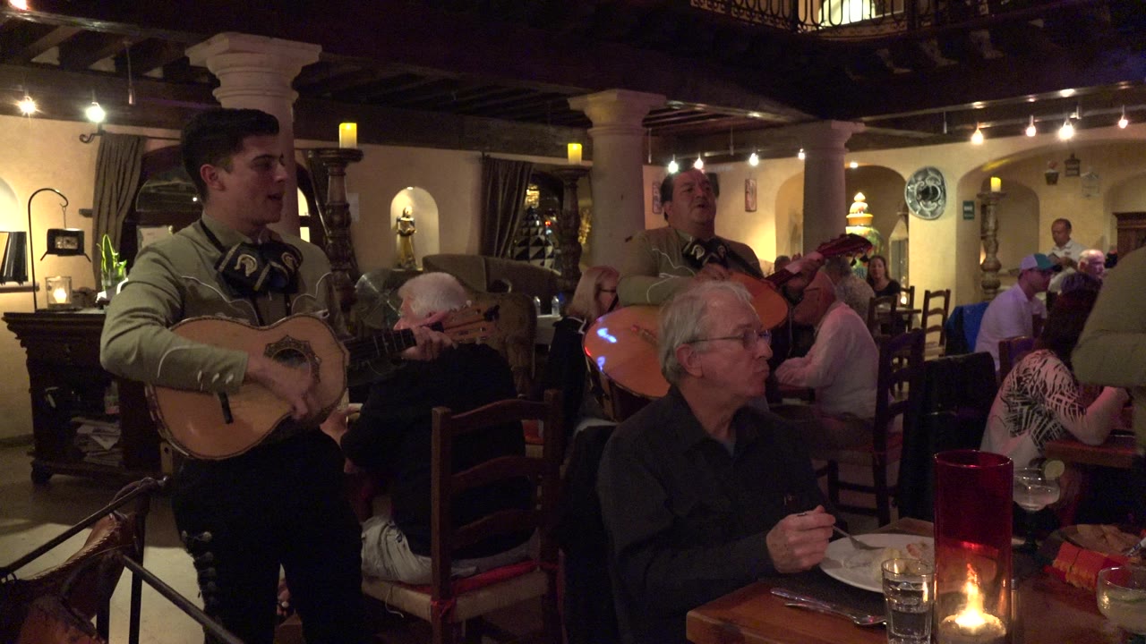 Musician playing beside candlelit restaurant tables.