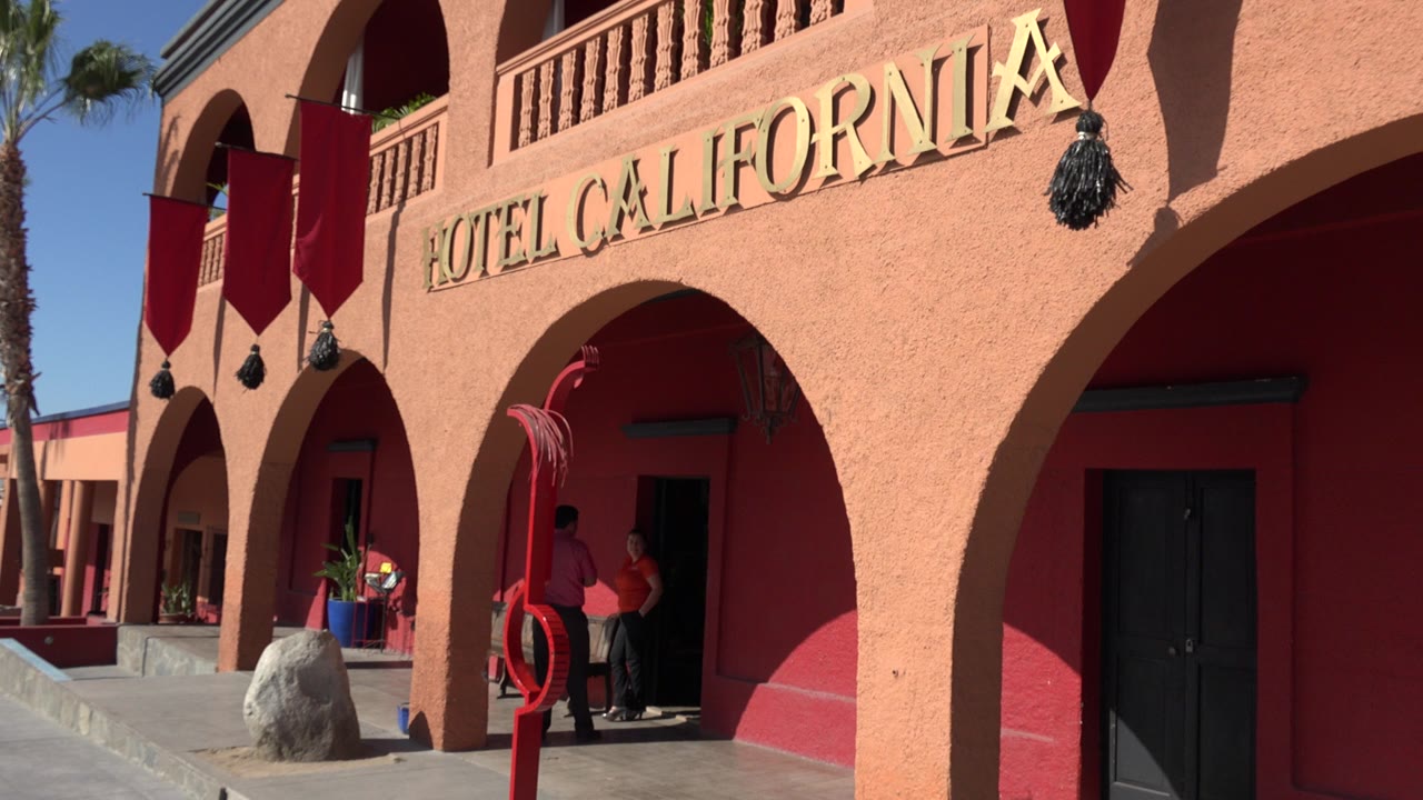 Crimson hotel facade with Hotel California sign and flags