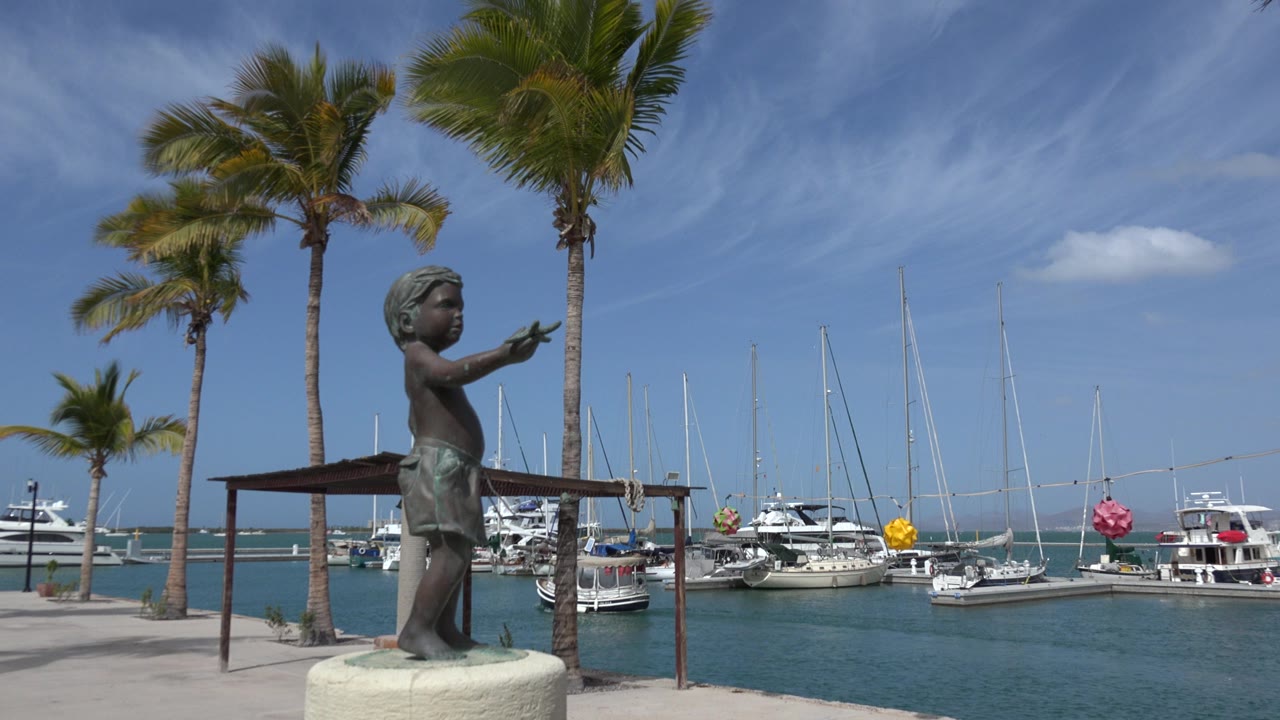Boy statue beside palm trees and marina boats